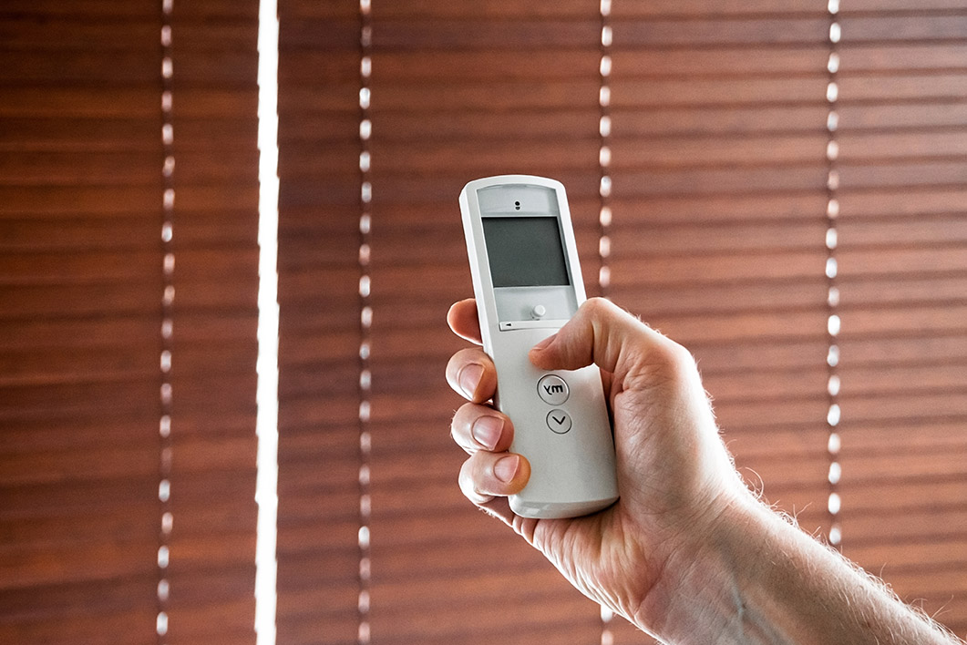 male hand holds a remote control to open the window blinds