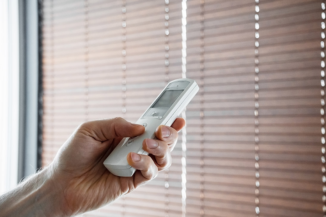 male hand holds a remote control to open the window blinds